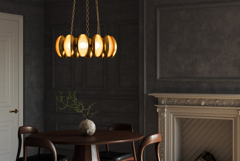 Brushed gold oval disc cluster chandelier on brass chain over round walnut dining table in dark moody panelled dining room
