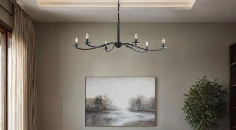 Wrought iron 6-arm candelabra chandelier with exposed candle bulbs in warm neutral living room with linen sectional and coffered ceiling