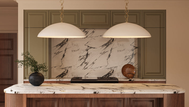 Pair of oversized cream dome pendants on brass chain over fluted walnut kitchen island with thick marble countertop