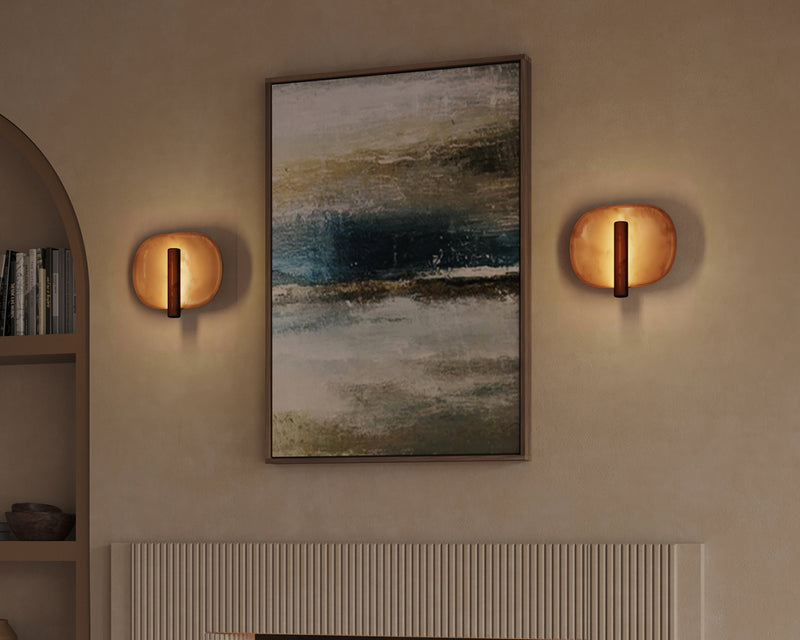 Amber resin disc wall sconces flanking large abstract canvas above ribbed plaster fireplace surround in warm terracotta living room