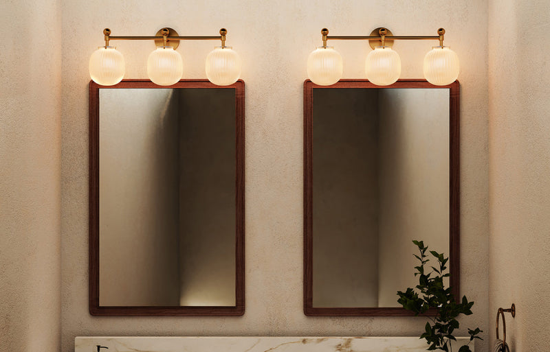 Antique brass 3-globe vanity light bar with ribbed opal glass shades above double undermount marble sink vanity with walnut-framed mirrors